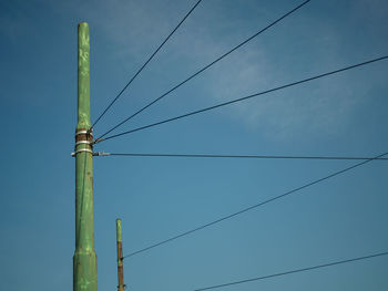 Low angle view of electricity pylon against blue sky