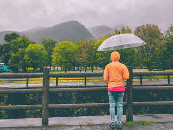 Rear view of woman holding umbrella