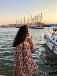 Candid millennial girl is in marina in bodrum surrounded by yachts with sunset on a background