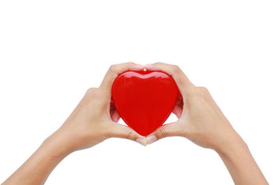 Close-up of hand holding heart shape against white background