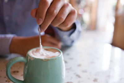 Cropped image of hand stirring coffee at home