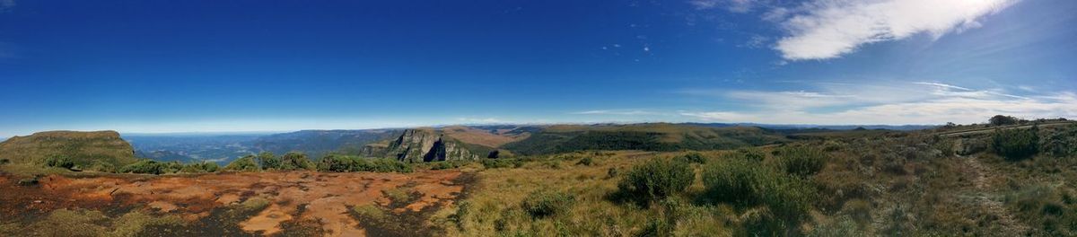 Panoramic shot of countryside landscape against blue sky