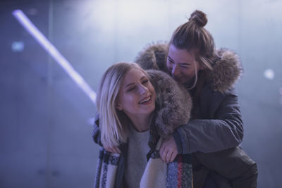 Smiling young woman giving piggyback to friend 