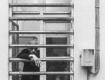 Rear view of woman standing by window of building