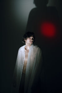 Young man looking away against black background