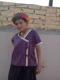 Portrait of girl in traditional clothing while standing against wall