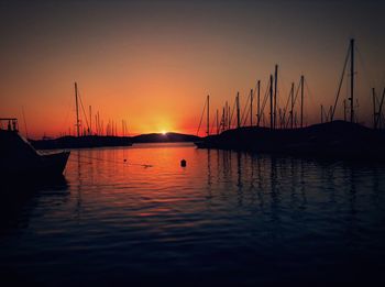 Sailboats in sea at sunset