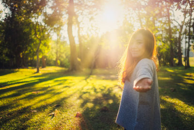 Portrait of woman standing by tree on field