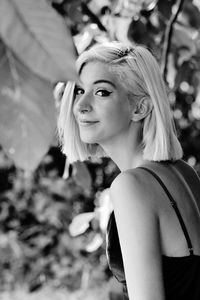 Portrait of smiling young woman standing by plants