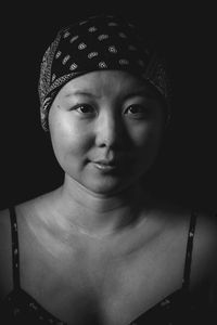 Close-up portrait of smiling young woman over black background