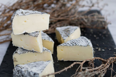 Close-up of cheese slices amidst herbs on cutting board in kitchen