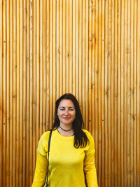 Portrait of woman standing against wooden wall