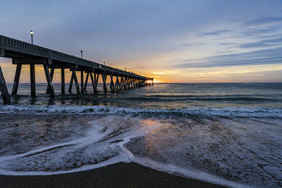 Pier over sea against sky during sunset