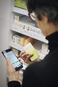 High angle view of senior woman using smart phone for checking medicine at store