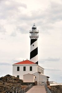 Lighthouse in city against sky