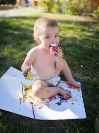 Portrait of shirtless boy playing with watercolor paints