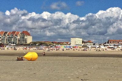 People on beach in city against sky