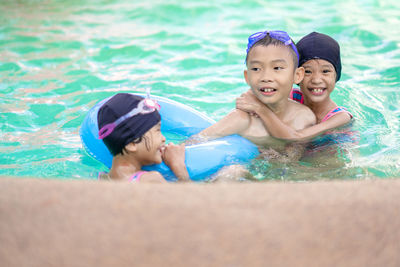 Portrait of happy siblings in swimming pool