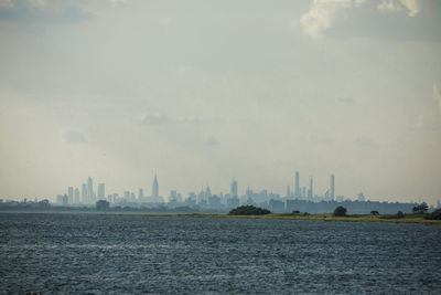 City buildings by sea against sky