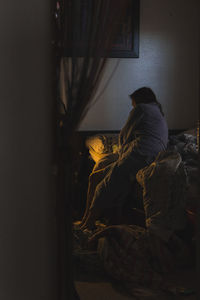 Rear view of woman sitting in bedroom