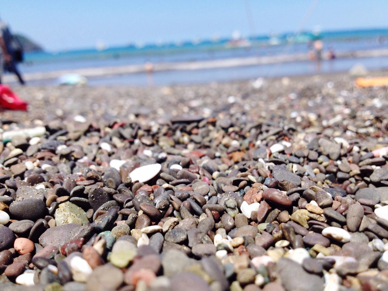 beach, pebble, surface level, selective focus, abundance, sea, large group of objects, shore, stone - object, sand, focus on foreground, tranquility, nature, day, stone, horizon over water, water, outdoors, tranquil scene, close-up