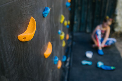 Unrecognizable blurred girl sitting near climbing wall with plastic grips in contemporary gym
