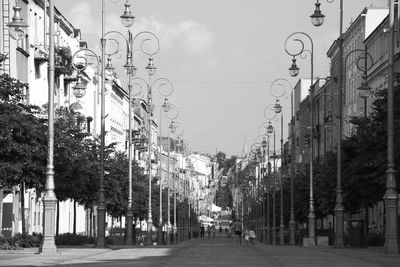 Street amidst trees in city against sky