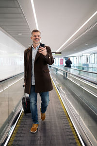 Full length portrait of man walking on escalator