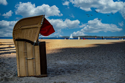 Hooded beach chairs on shore against sky