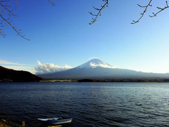 Scenic view of lake by mountains against clear blue sky