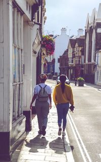 Rear view of  women walking on street amidst buildings