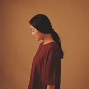 Side view of young woman standing over brown background