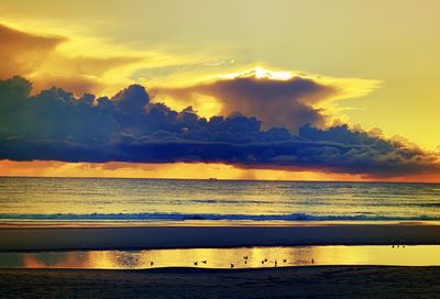 Scenic view of sea against dramatic sky during sunset