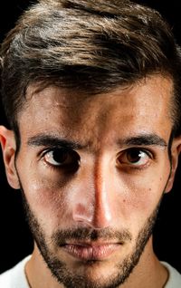 Close-up portrait of young man against black background