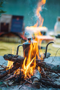 Preparing coffee or tea on an bonfire with branches and flames outdoor in the nature, vertical