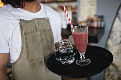 Midsection of owner holding drink in serving tray at restaurant