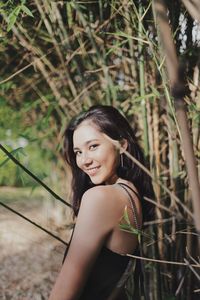 Portrait of young woman standing by plants