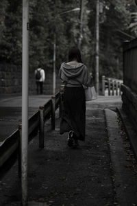 Rear view of man walking on footpath