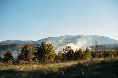 Autumn mountains landscape with smoke under the hills