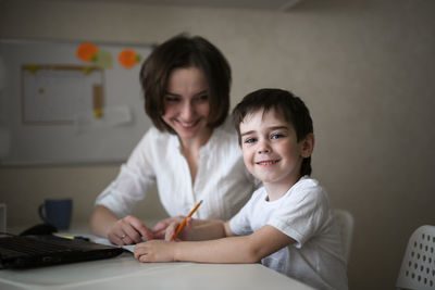 Happy mother is engaged in a laptop with her son preschooler, a real european interior, 