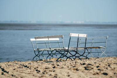 Empty chairs on shore at beach