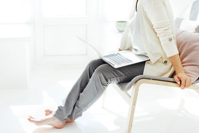 Midsection of woman using mobile phone while sitting on table