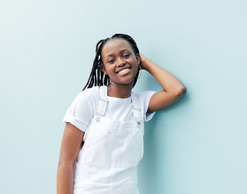 Portrait of young woman standing against white background