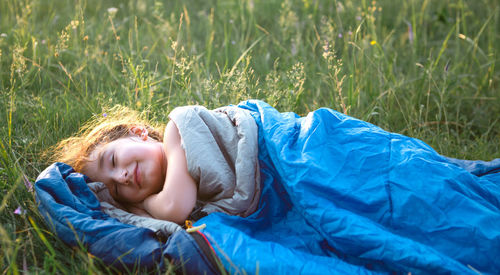 Cute girl in sleeping bag on field