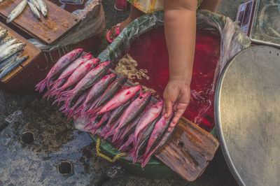 Cropped hand of woman arranging fish on wood at market