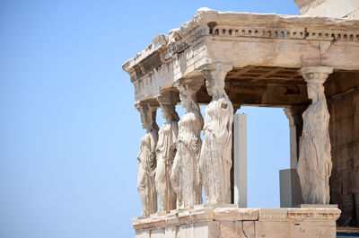 Low angle view of sculptures at historic building against clear sky