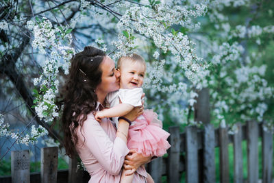 Mother with daughter embracing by cherry tree