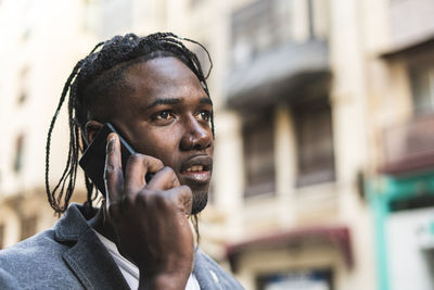 Close-up of young man talking on mobile phone in city