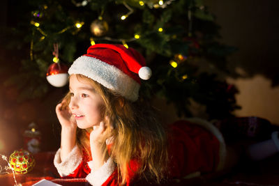 Cute girl lying down by illuminated christmas tree