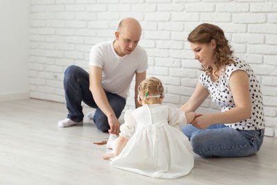 Side view of couple sitting on hardwood floor